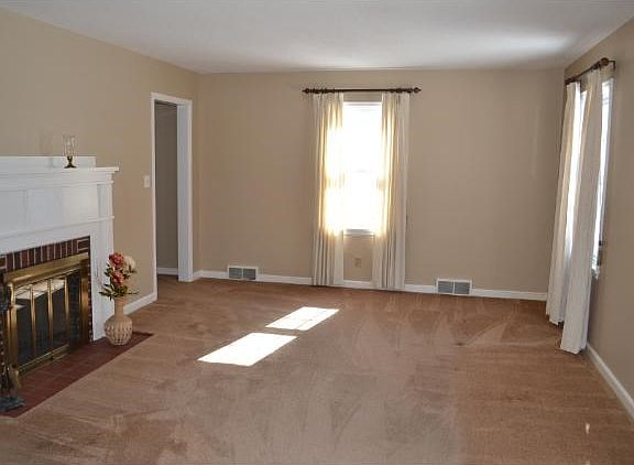 Spacious living room has a wood burning fireplace and large windows offer tons of natural light.