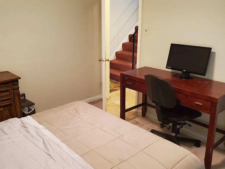 Private bedroom with a bed, work desk and chair, and a TV setup, plus convenient access to the hallway/stairs.