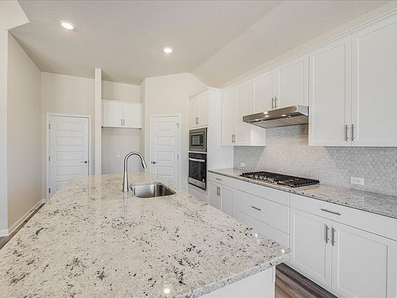 This gorgeous kitchen features linen-colored cabinets and granite countertops.