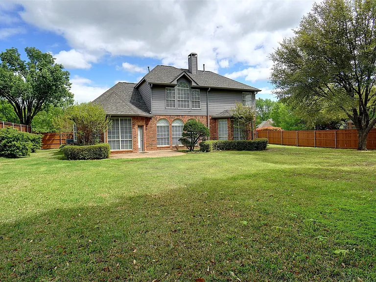 Expansive backyard featuring a large green lawn, mature trees, and a privacy fence
