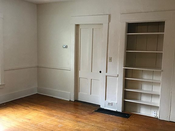 Living room with wood flooring, natural light, built ins, and ceiling fan.