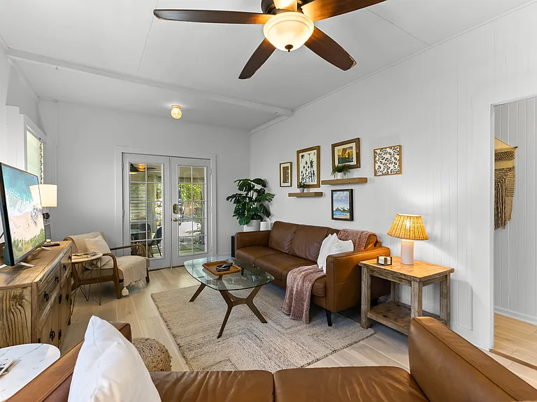 The living room includes an Italian leather sofa and loveseat and one chair, TV, ceiling fan, windows and an AC unit. The living room opens to the lanai and blends seamlessly with the kitchen.