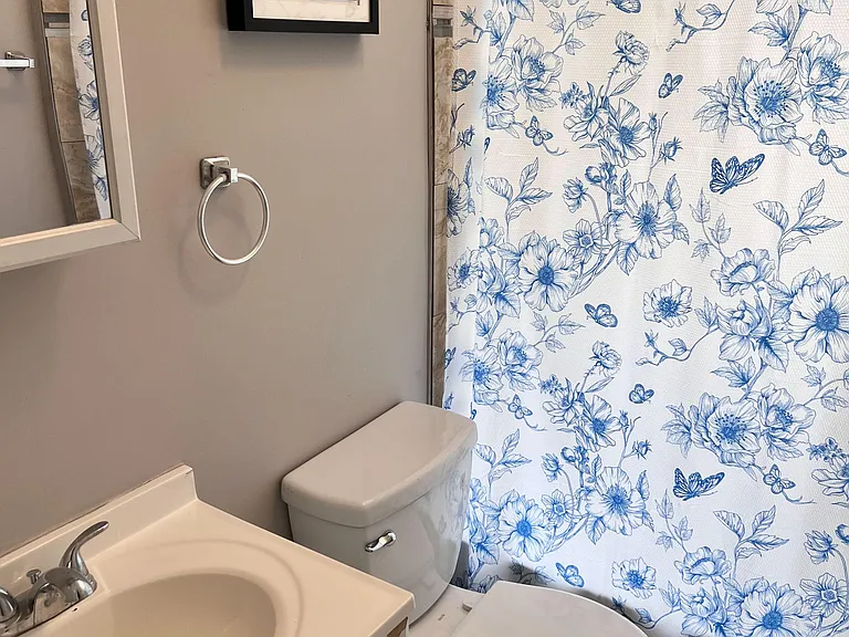 Full bathroom with a vanity sink, mirrored medicine cabinet, and tub/shower combo with tiled surround and curtain.