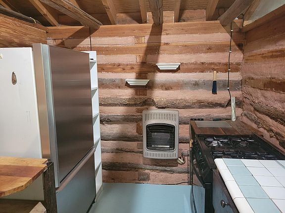 Second portion of kitchen with gas range and stainless steel fridge. No dishwasher.