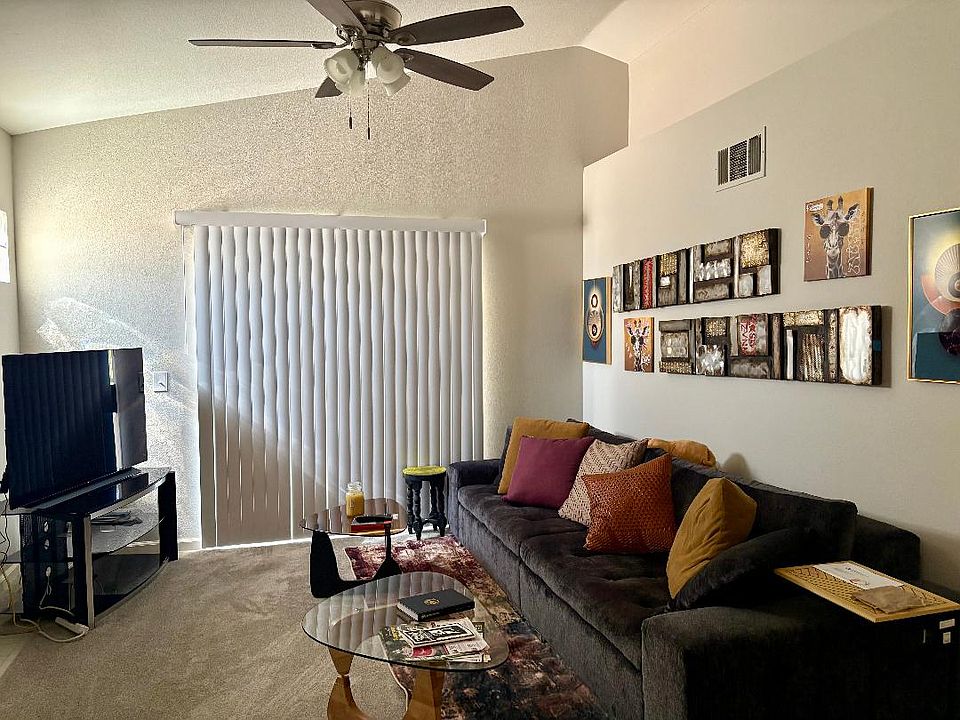 Furnished living room with ceiling fan, couch, gas fireplace and flat screen TV with stand.