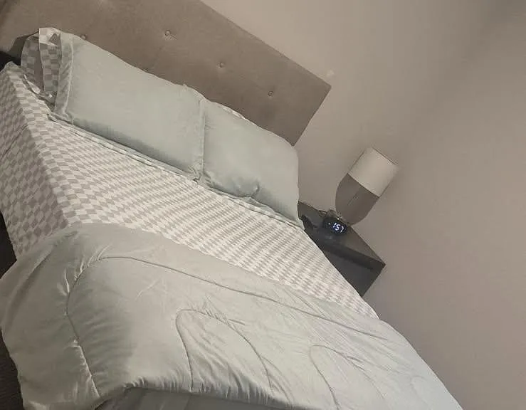 Furnished bedroom featuring a full bed with upholstered headboard and a bedside table with lamp for convenient nighttime use.