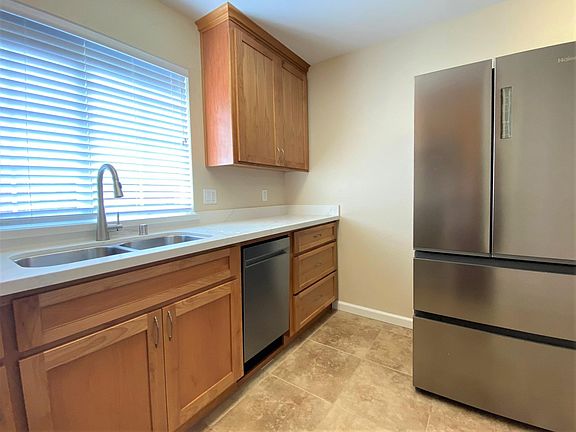 Kitchen with double-sink, garbage disposal, dishwasher, and full-sized refrigerator. Plenty of cabinet storage.