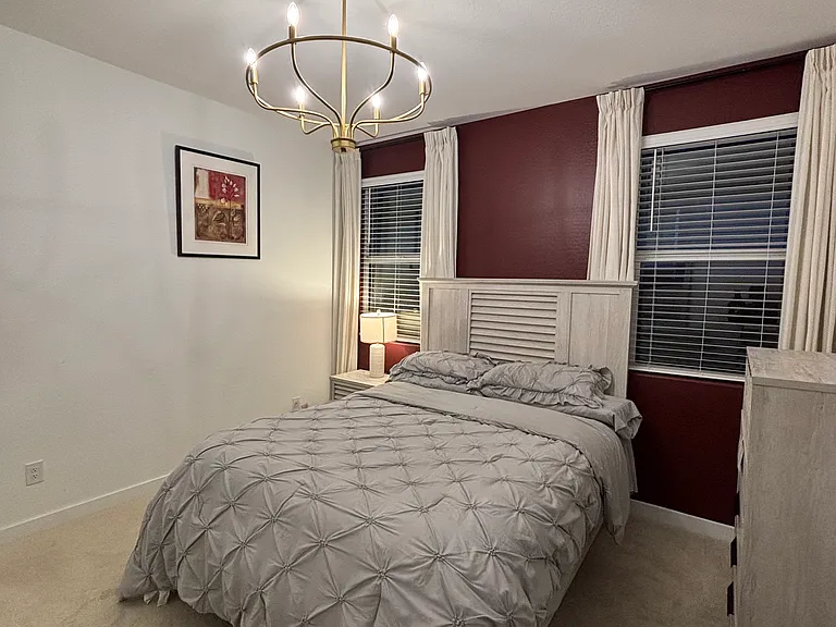Primary bedroom featuring queen bed set with night stand plus lamp, dresser with mirror and wardrobe, walk in closet, and chandelier