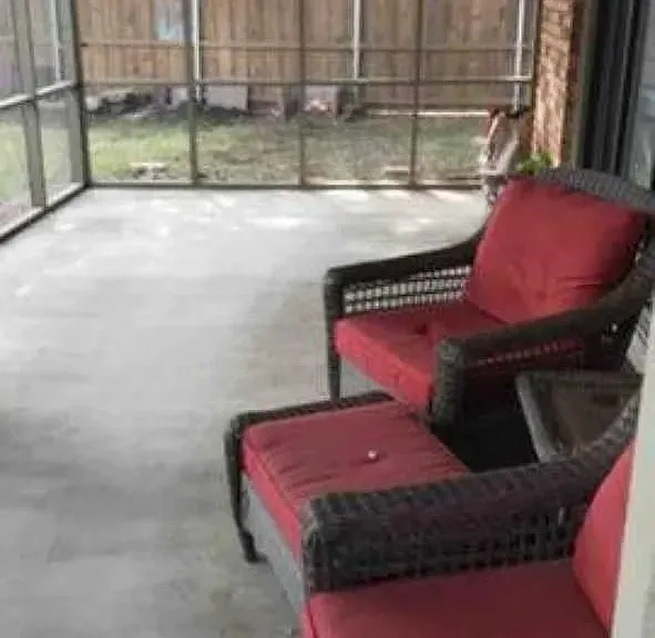 Screened patio with a concrete floor, featuring brick exterior walls and a wooden privacy fence