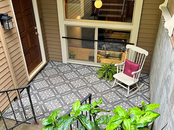Covered front porch with wrought iron railings, coat rack, and raised garden.