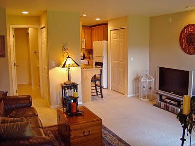 View of living room looking towards kitchen and bath. Bathroom has extra storage, tile floor and sho