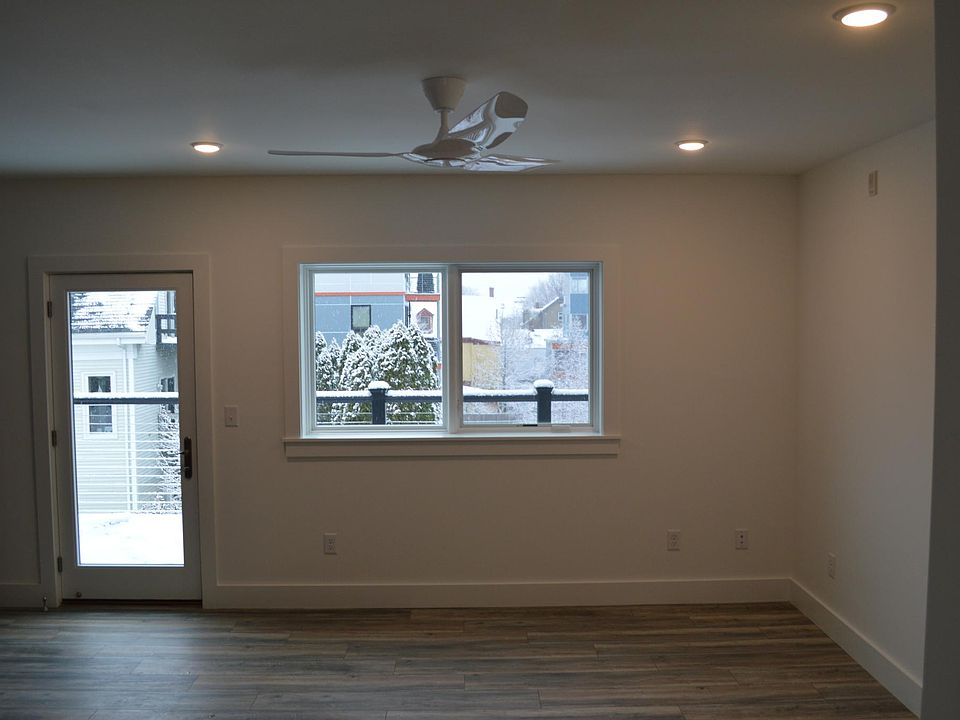 Living room with large windows and door to private balcony (shown unfurnished).