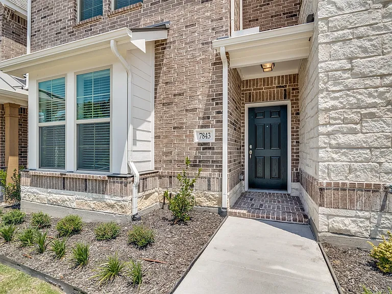 Brick and stone facade featuring a paneled front door under a covered entry