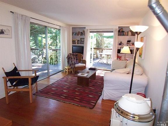 Living room with slider and french doors leading to the deck. Leaf design on wood flooring.