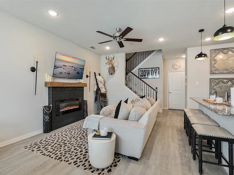 Open-concept living space featuring a built-in fireplace with a wood mantle, recessed lighting, and wood-finish flooring