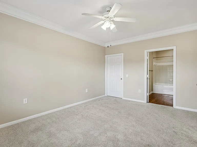 Bright and spacious bedroom featuring fresh carpet, a ceiling fan, and a private bathroom entrance. Bright and spacious bedroom featuring fresh carpet, a ceiling fan, and a private bathroom entrance.