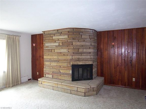 Living room with cherry walls and stone wood burning fireplace with insert...HARDWOOD under carpet