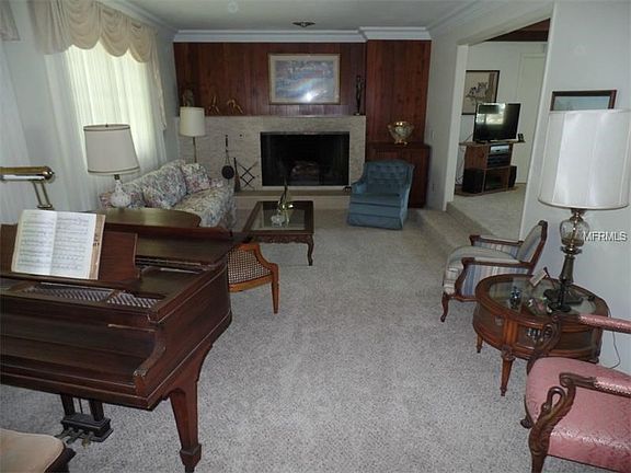 Sunken living room with plaster crown molding and wood-burning fireplace