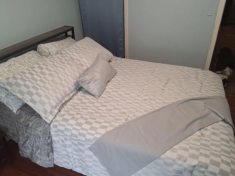 Furnished bedroom with a full-size bed, wood frame, and easy access to the hallway for everyday convenience.
