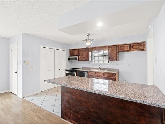 Kitchen featuring baseboards, stainless steel appliances, a textured ceiling, light wood-type flooring, and a sink