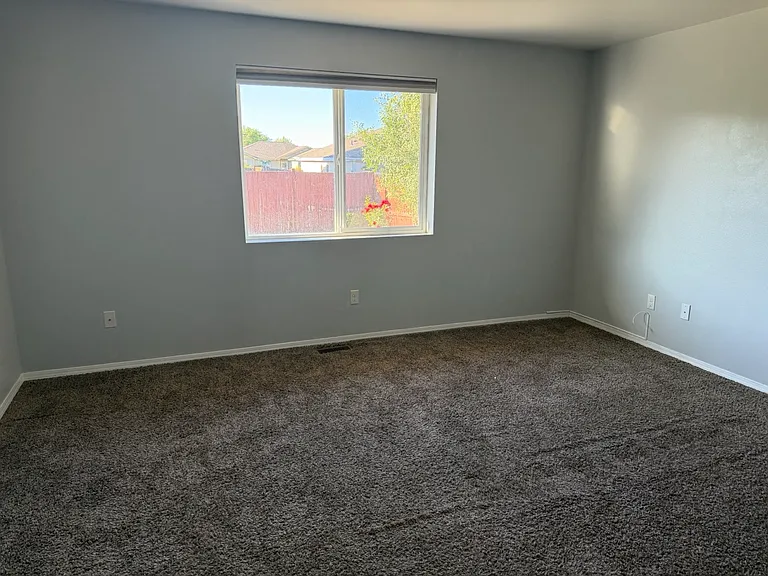 Master bedroom featuring large window into the backyard, with blinds. The carpet has been stretched since this photo was taken. No seams are present.