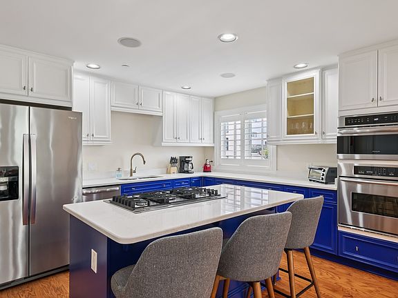 Modern kitchen with bold blue lower cabinets, white uppers, and center island cooktop.