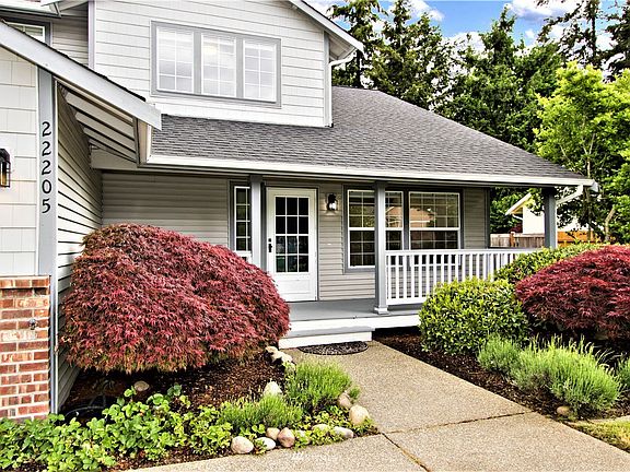Walkway leading up to large porch with Japanese maples on each side