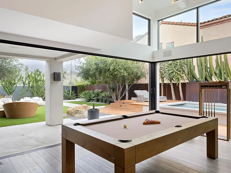 The pool table is perfectly placed near the outdoor lounge and pool.