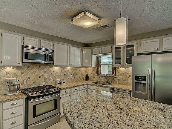 Gorgeous kitchen with granite counter tops and modern light fixtures! A great space to entertain fam