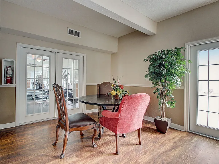 Elegant dining area with stylish furnishings and natural light, featuring a cozy round table, chic chairs, and indoor plants.