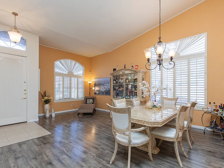 Spacious dinning & living room featuring vintage oak wood-look flooring, vaulted ceilings & window wood shutters