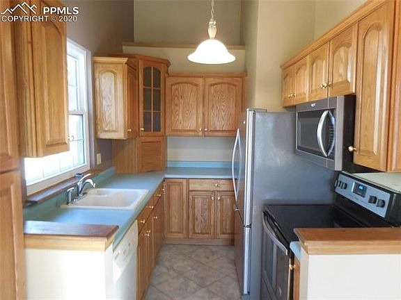 Pretty kitchen has light oak cabinets and tile floor.