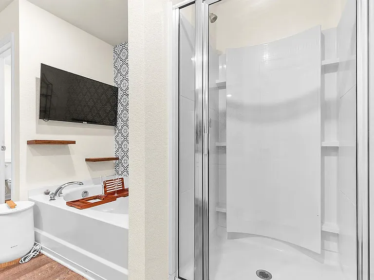 Unwind in a spacious master bedroom featuring a gorgeous accent wall and ample natural light. The attached master bath is a true oasis, complete with a deep soaking tub, a separate shower, a beautiful modern accent wall, and shelving.