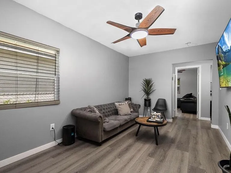 Comfortable living area with ceiling fan, wall-mounted TV, and easy-care flooring, plus a window for natural light.