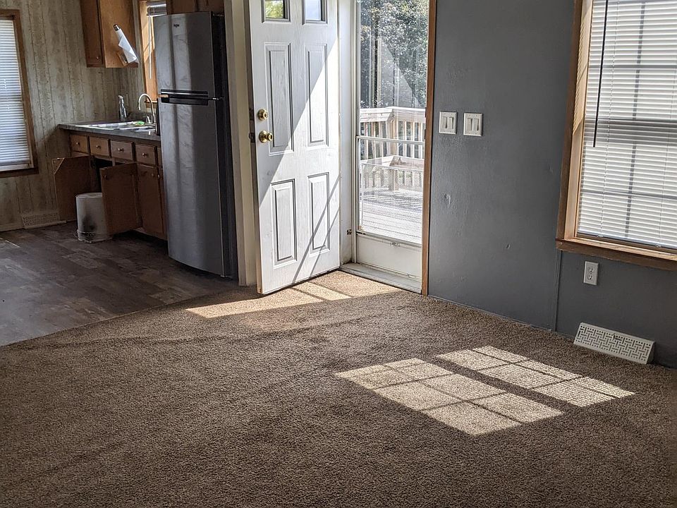 Entrance into livingroom off large front deck. Freshly painted 2 contrast walls in gray tone. Carpet on floor. Vaulted ceiling in livingroom w/ceiling fan. Mini blinds on windows.