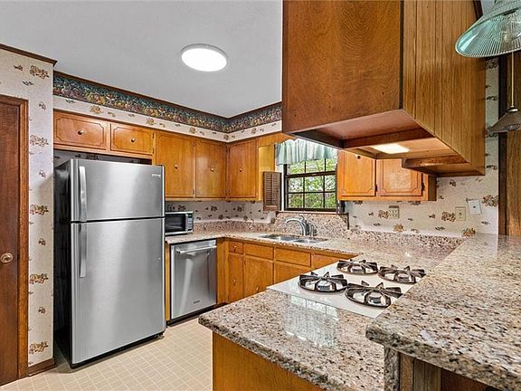 Carpeted empty room with a textured ceiling, a notable chandelier, baseboards, and visible vents