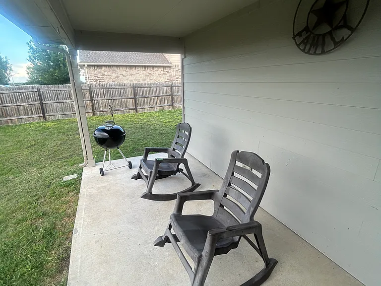 Backyard patio with grill, and two rocking chairs