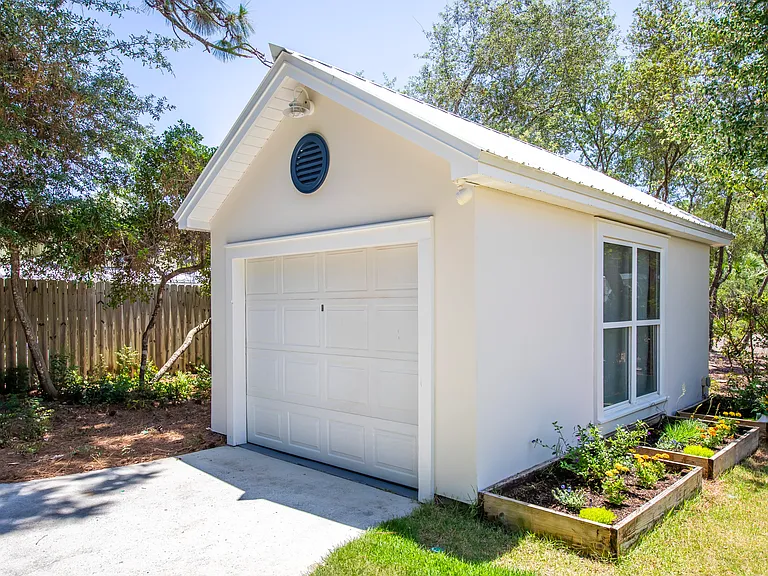Detached garage and three raised garden beds with flowers.
