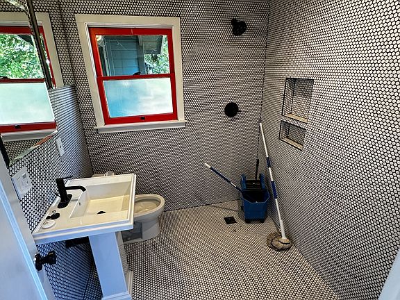 Bathroom with tiled walls and ceilings and floor drain for easy cleaning.