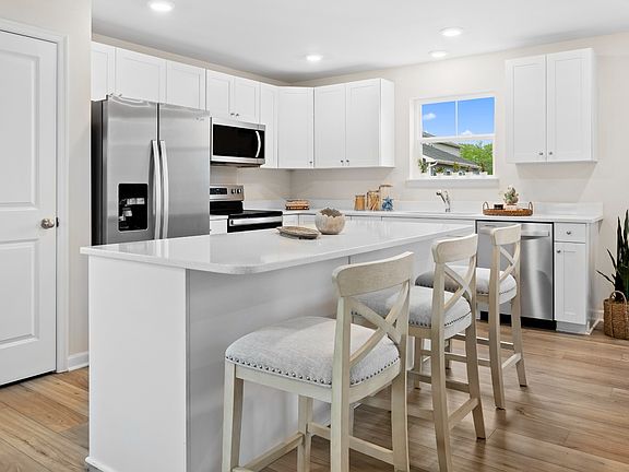 Island kitchen with white cabinets in a DRB Homes Whitehall model home at The Village of College Pa