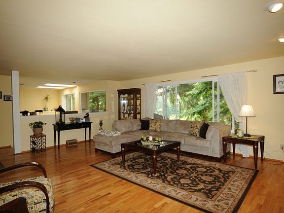 Huge Living Room Features Beautiful Hardwoods & Wall of Windows & Skylights