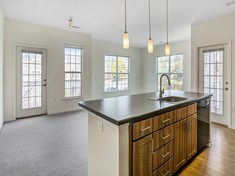 Bright and modern kitchen with sleek island, stylish pendant lighting, and abundant natural light from large windows.