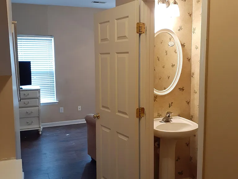 Compact half-bath with pedestal sink and vanity lighting, conveniently located off the main room for easy access.