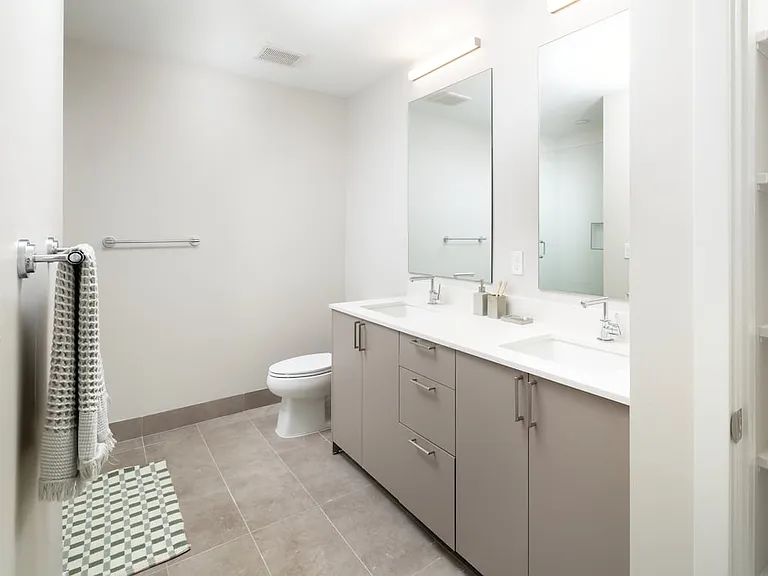Upgrade Collection I primary bath with double-sink vanity, white quartz countertops, standing shower, and built in linen closet with shelving