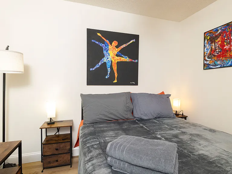 Bright bedroom with a comfy queen bed, dedicated workspace, large windows, and modern decor. Peaceful, stylish, and perfect for working or unwinding.