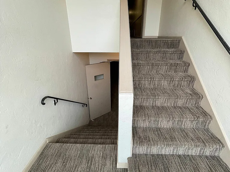 Explore the sleek design of this apartment's staircase, offering seamless access to upper levels.