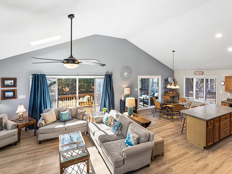 Open-concept living, dining, and kitchen area with large sliding glass doors leading to the rear deck and screened porch, creating a bright, connected space for relaxing, dining, and entertaining.