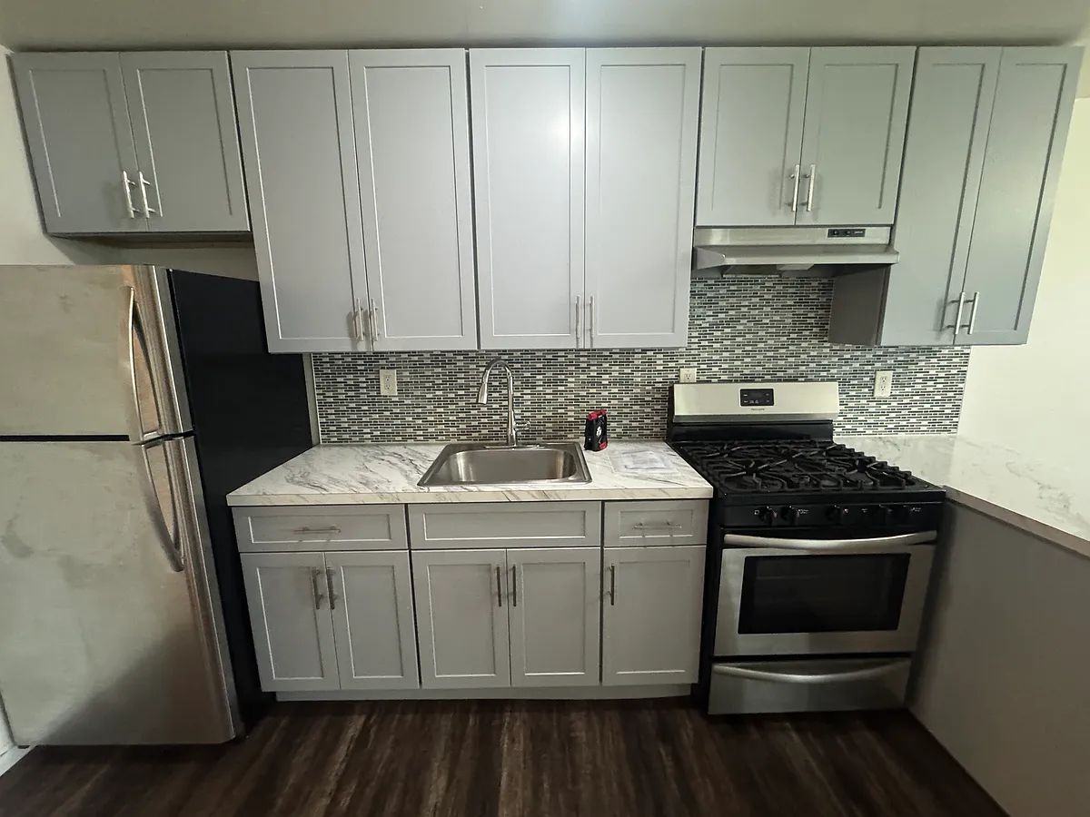 Stylish, updated kitchen with sleek cabinetry, mosaic tile backsplash, and stainless steel fridge and gas stove. Clean, modern look with practical layout. - Throggs Neck Expy