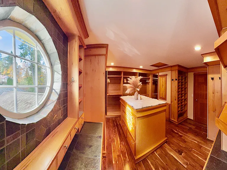__ Luxe Walk-In Closet & Dressing Room Indulge in a beautifully designed walk-in closet featuring custom wood cabinetry, mirrored doors, and recessed lighting. A central island with drawers and cubbies offers elegant storage, topped with a plush faux fur