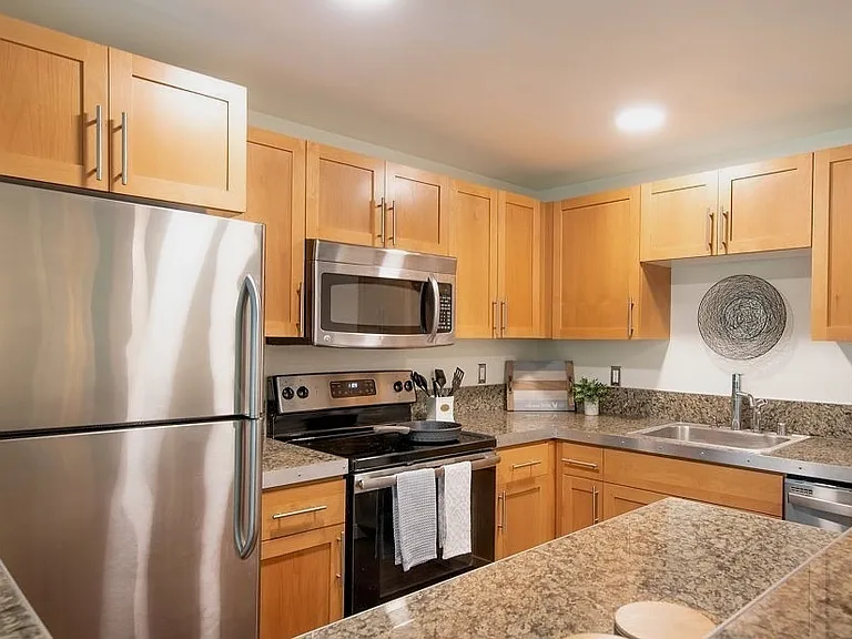 Kitchen includes generous storage space (large cabinets / drawers and extra storage above cabinets), sleek stainless steel appliances, solid kitchen island